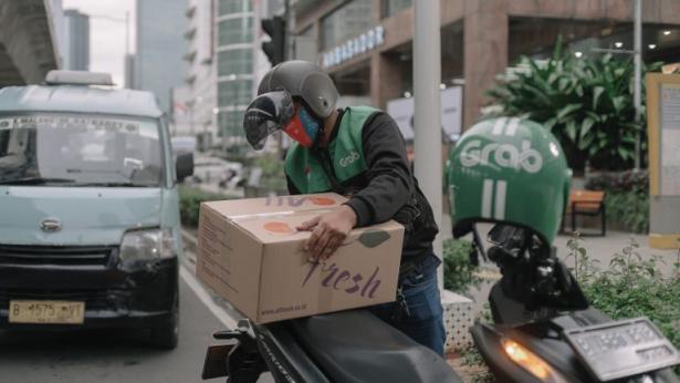 Grab driver loading a cardboard box onto their bike.