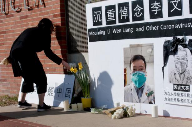 Women places a flower next to a photo of Dr. Li Wenliang
